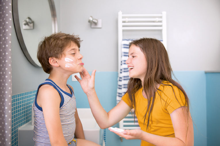 Photographie lifestyle de familles et d'enfants qui mettent de la crème dans la salle de bain