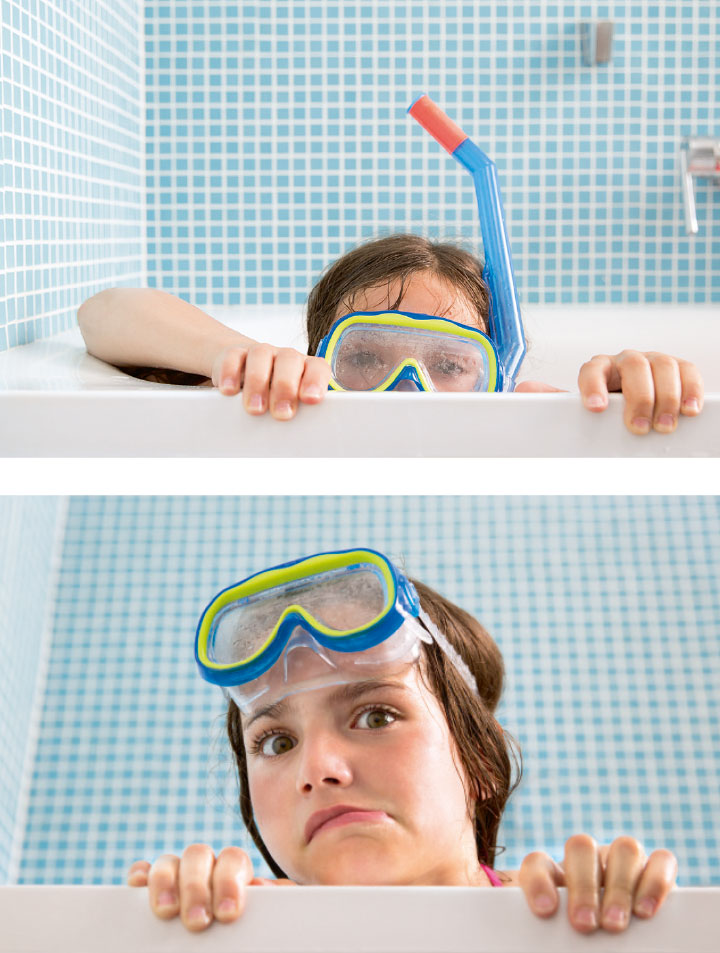 Photo lifestyle enfant petite fille dans son bain à jouer avec l'eau