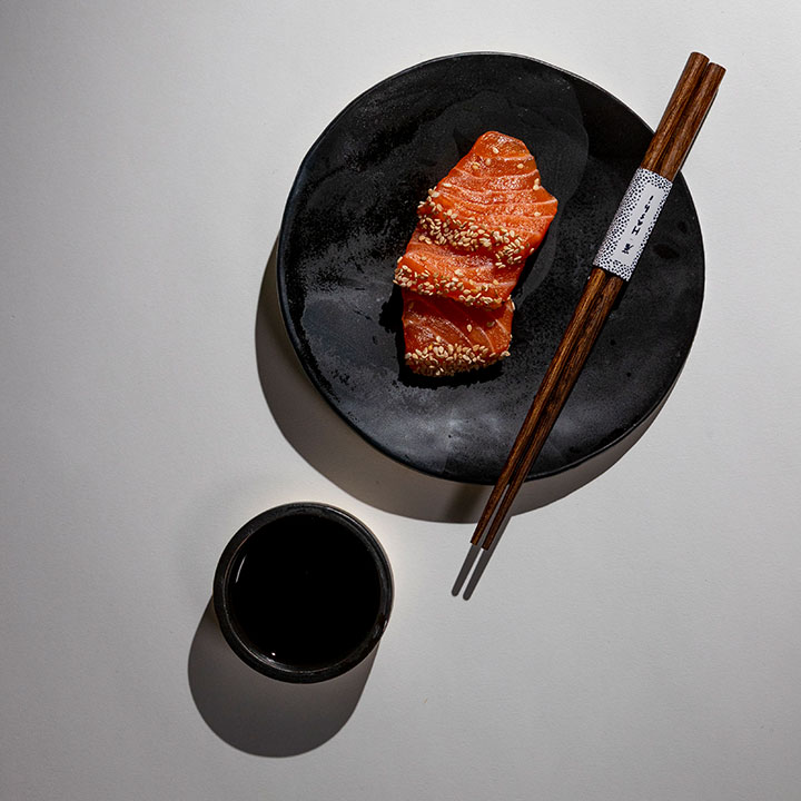 Tranches de saumon de cuisine japonaise dans des céramiques blanches et baguettes en bois